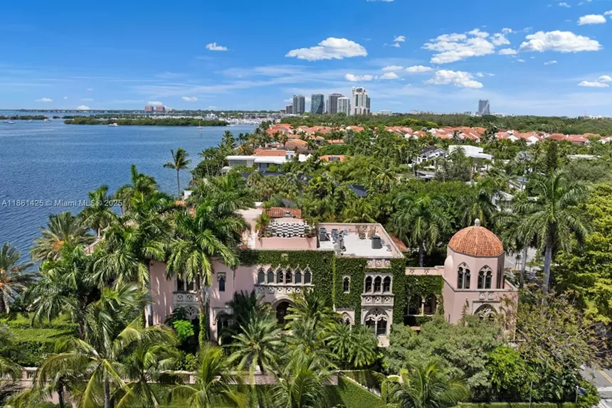 Depicted is a gothic-style mansion covered in a thicket of lush South Florida foliage.