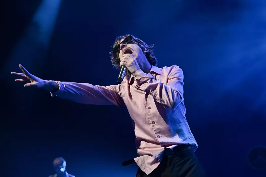Picture of a singer on stage holding the microphone and extending his hand.