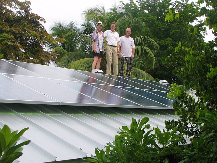 Gray Read and Phil Stoddard on the solar-paneled roof of their South Miami home, which has lowered their FPL bill to less than $10 a month. The man on the right is the installer of the solar panels, Danny Upchurch. - COURTESY OF BRADLEY STARKT