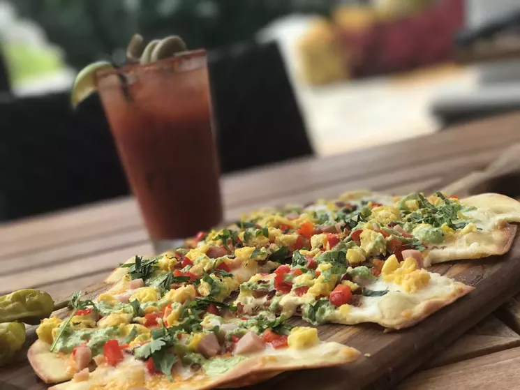 Breakfast flatbread: Wheat-flour crust topped with scrambled eggs; Alfredo sauce; roasted peppers; jack, cheddar, and mozzarella cheeses; applewood-smoked and Canadian bacon; and a drizzle of cilantro cream. - COURTESY OF BRIMSTONE