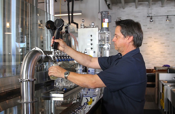 Mathews Brewing Co. owner and brewer Dave Mathews pours beer in his Lake Worth taproom. - PHOTO BY NICOLE DANNA