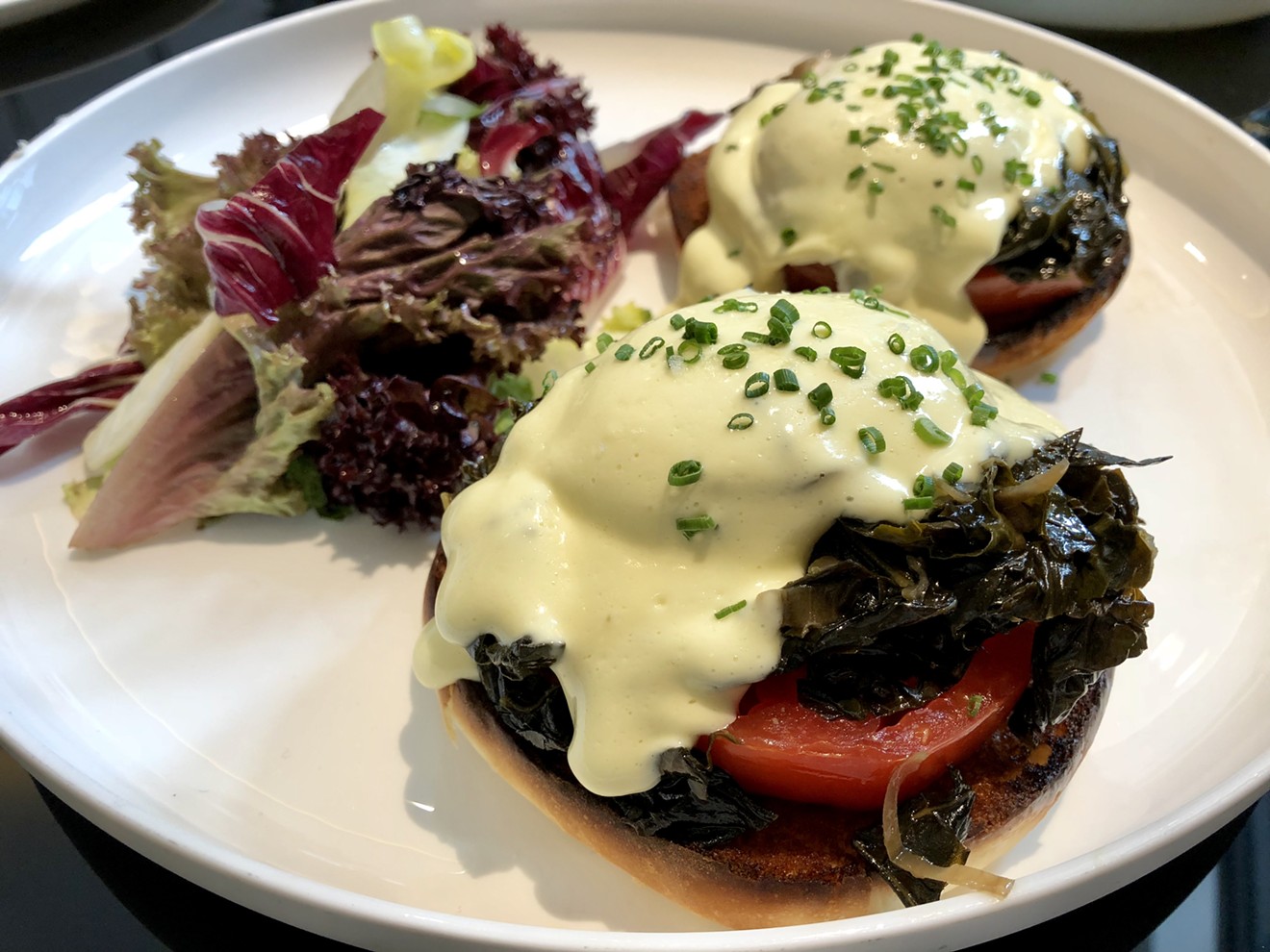 Eggs Benedict with tomato and kale.
