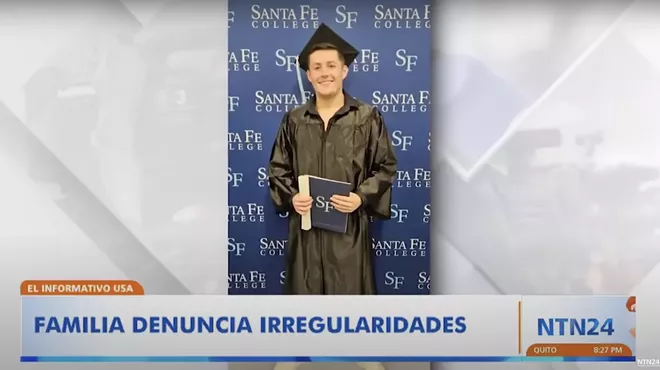 Photo of a young man in a black graduation cap and gown in front of a Santa Fe College banner.
