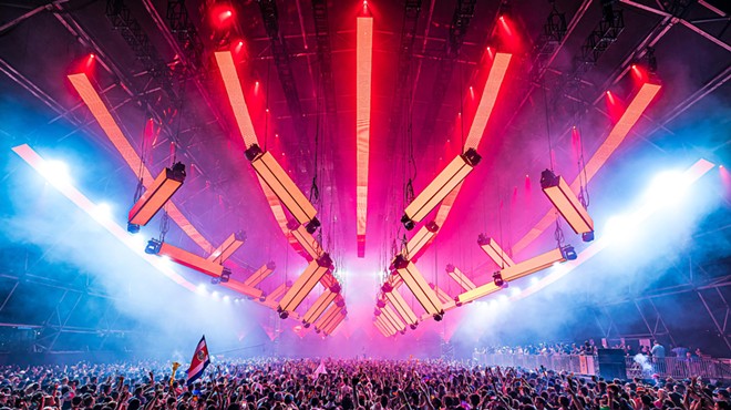 Festivalgoers dancing under massive LED lights hanging overhead