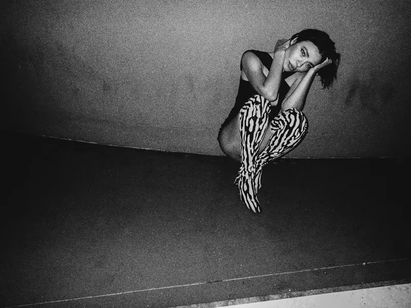 Image: Nina Kraviz kneeling against a wall