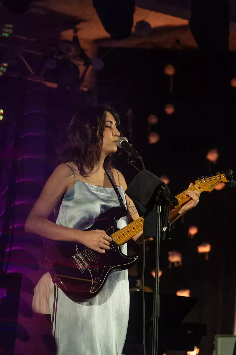 Image: Singer Vania Junco plays guitar and sings on stage
