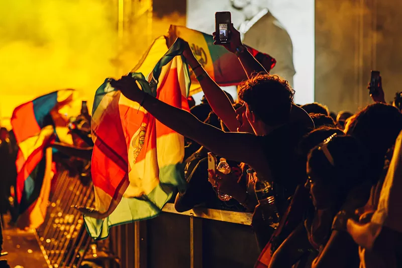 Image: An audience member waves a flag at the Vibra Urbana music festival in Miami