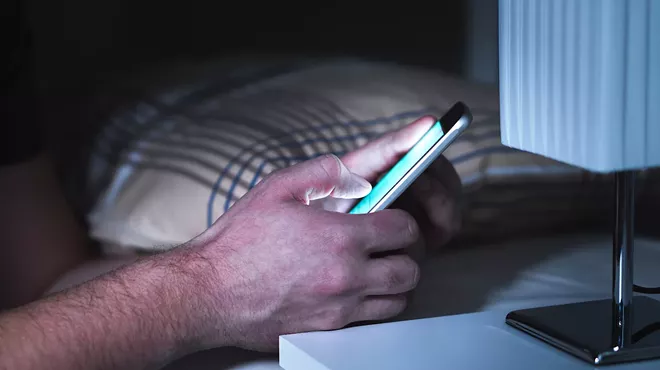 closeup of a man's hand texting in bed