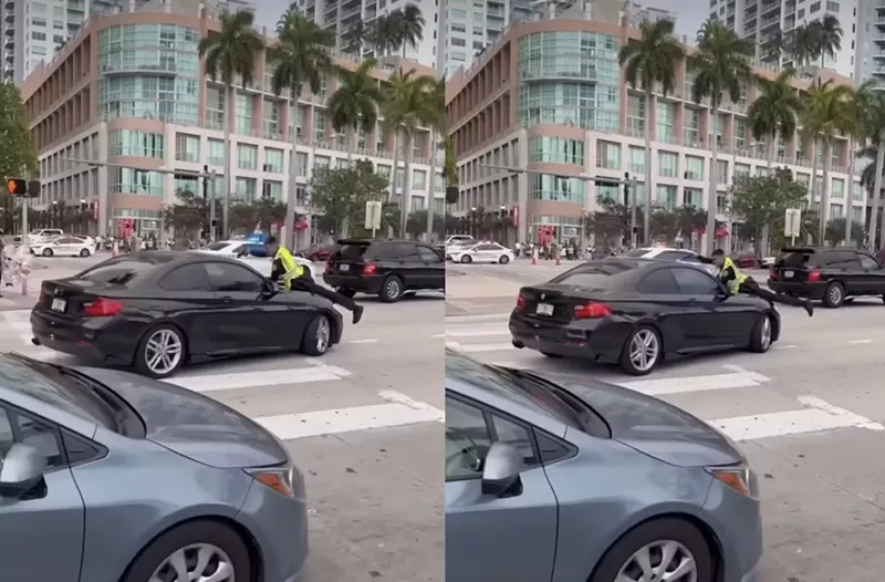 Image: Cell phone video shows a Miami police officer clinging to the hood of a man's car while firing shots through the windshield.