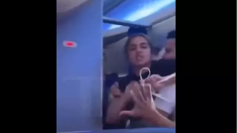 Image: Enraged woman restrained by a flight attendant