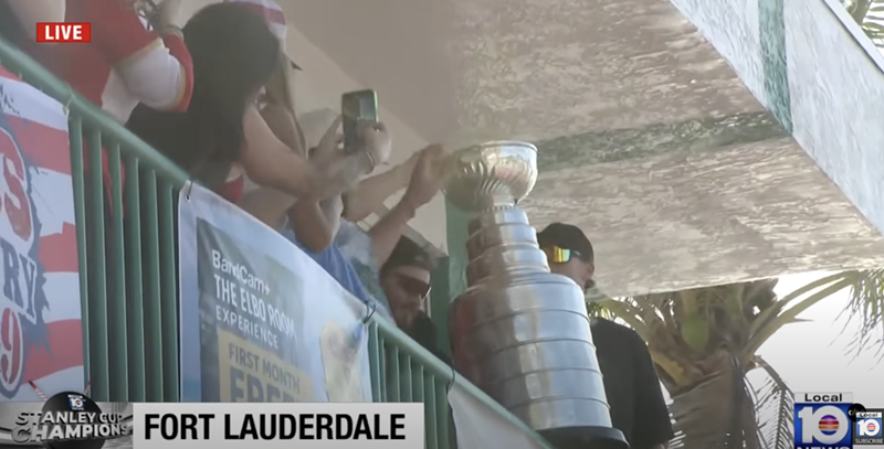 Image: Florida Panthers players hold the Stanley Cup on a balcony, surrounded by fans