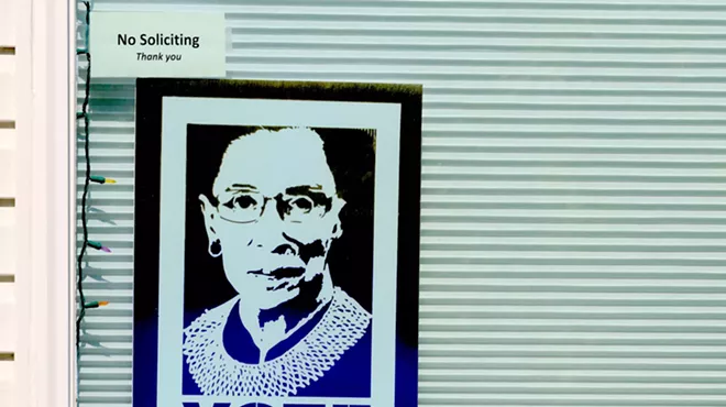 small Justice Ruth Ginsburg "VOTE" poster displayed in a window underneath a smaller "no soliciting" sign