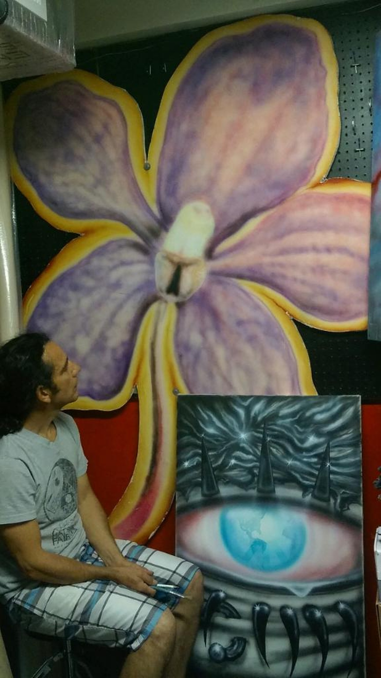 Wallflower alumnus Anibal Fernandez with the flower logo he painted on a chunk of drywall at the original gallery.