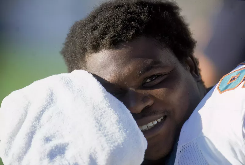 Image: Lineman Tim Bowens smiles as he wipes his forehead with a towel during a game