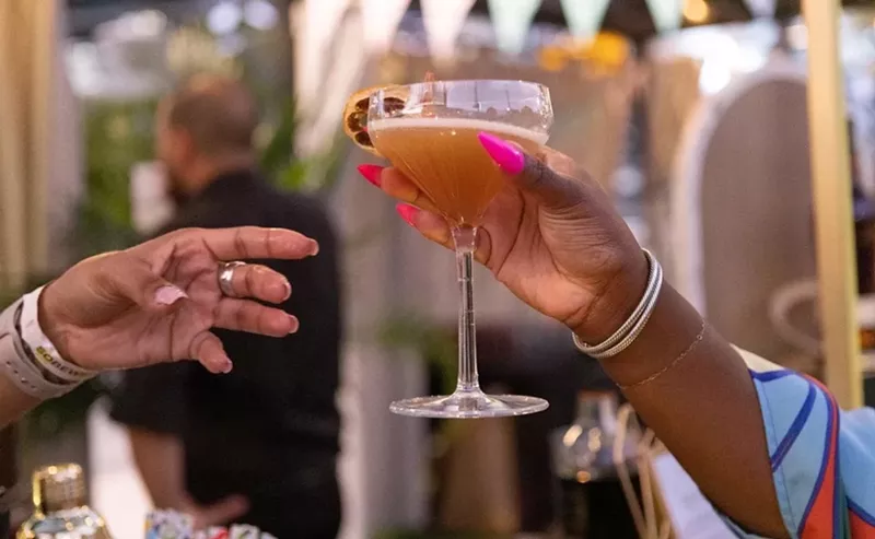 Image: Two people holding drinks in cocktail glasses