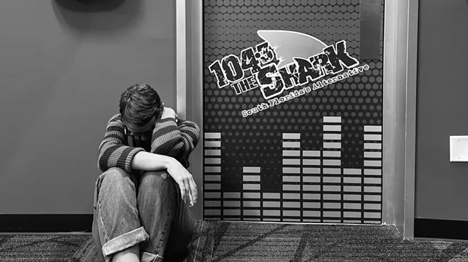 A woman sitting by a door outside a radio station