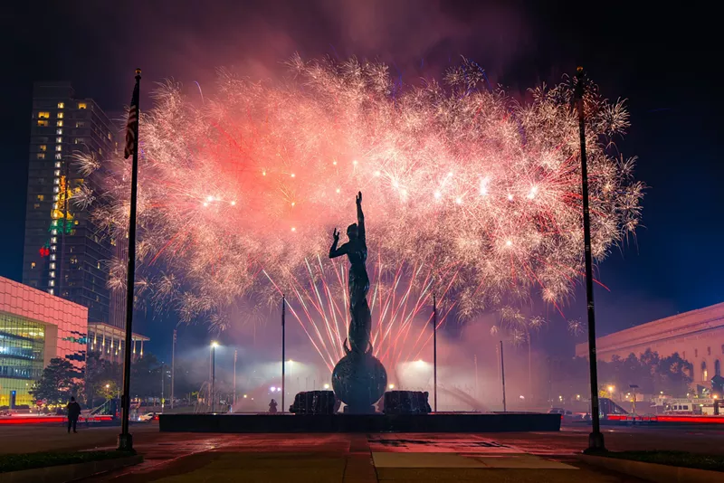 Image: A large cluster of fireworks explode with a statue silhouette in the foreground in Cleveland