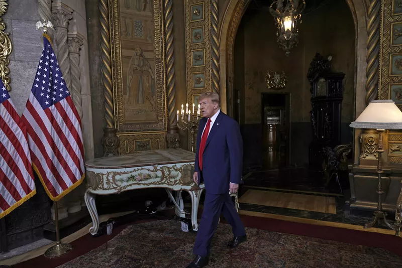 Image: Trump makes his way into a room at his Mar-a-Lago resort, walking next to a piano and elaborate gold-colored fixtures