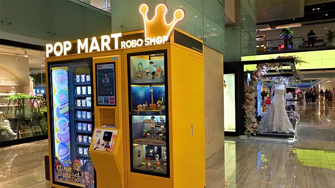 a yellow Pop Mart vending machine inside a mall