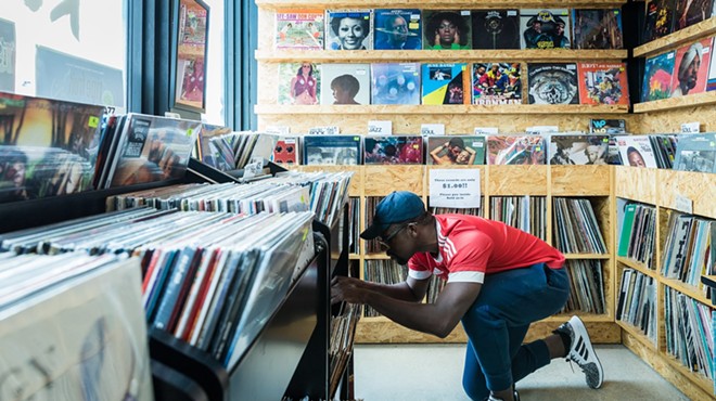 A man kneeling down while browsing for records