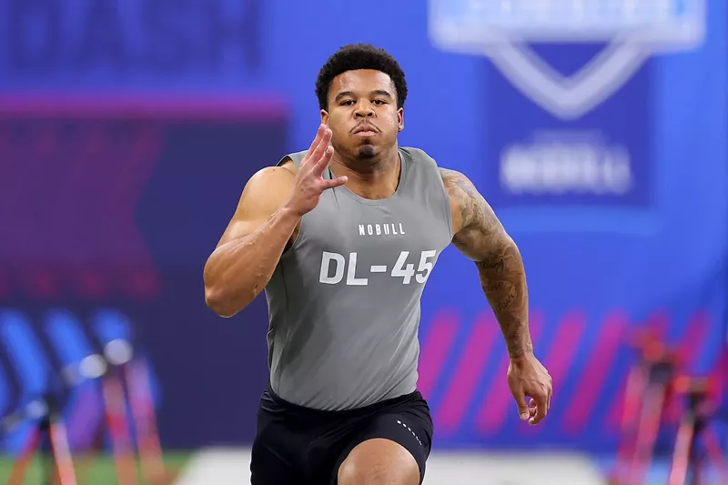 Image: Head-on shot of a sprinting football player wearing black shorts and a sleeveless gray shirt